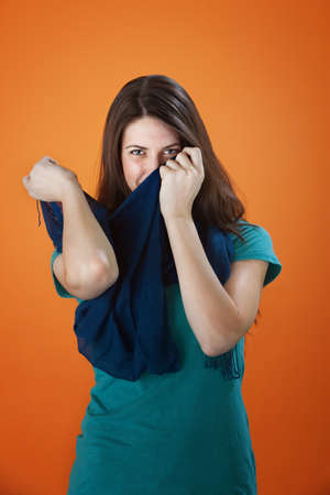 Shy young woman covering her mouth and nose with a scarfの写真素材