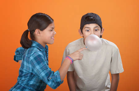 Girl touching a bubble blown by her brother with chewing gumの写真素材