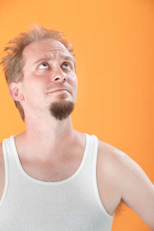 Worried Caucasian man on orange background looks upの写真素材