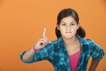 Fussy Latina child pointing index finger upward