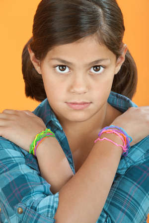 Little Hispanic Girl with arms crossed on an orange background