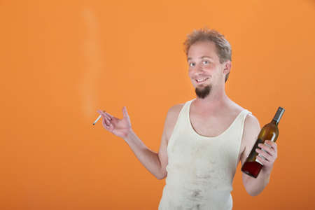Happy Caucasian man holding a bottle and a cigarette の写真素材