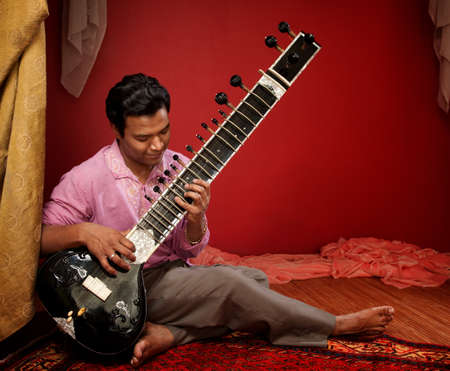 Handsome Indian man plays a Sitar indoorsの写真素材