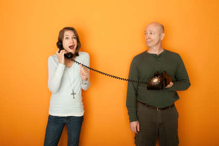 Excited Caucasian woman on telephone call with a middle-aged man on orange backgroundの写真素材