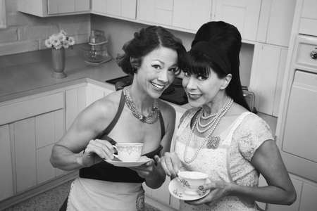 Two retro housewives with tea in a kitchenの写真素材