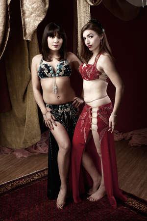Pair of gorgeous belly dancers with hands on thighs