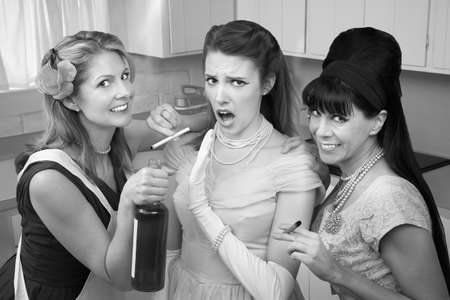 Young woman with her friends smoking and drinking in the kitchenの写真素材