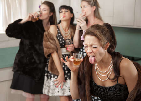 Woman reacts to strong alcohol while friends smoke and drink in the kitchenの写真素材