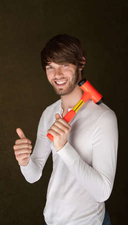 Handsome young man with mallet over his shoulder gives thumbs up