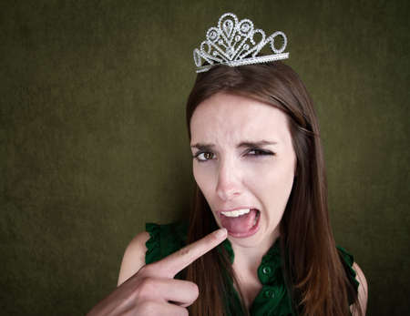 Disgusted Young Woman with a crown tiara and gagging gestureの写真素材