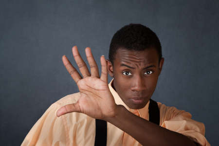 Young handsome Black male raises hand to block somethingの写真素材
