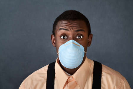 Worried young African-American man with surgical maskの写真素材