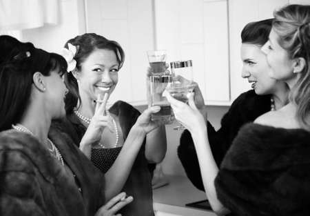 Group of four Caucasian women in a kitchen make a toastの写真素材