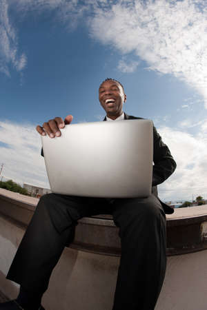 Excited African-American businessman relaxes while working on his laptopの写真素材