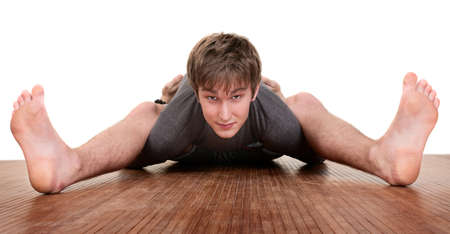 Flexible young Caucasian man exercises over white background