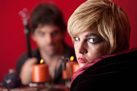 Serious Caucasian woman fortuneteller stares over maroon background