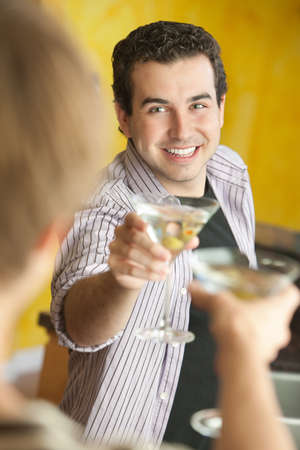 Young Caucasian man with friend makes a toast with martini glassの写真素材