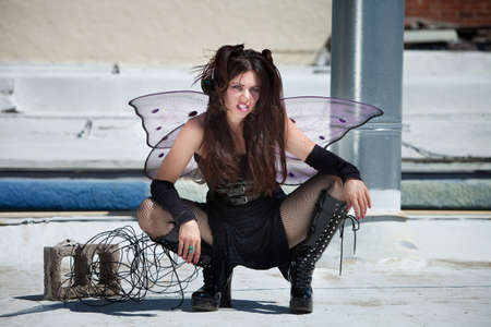 Attractive fairy sitting outdoors on a silver roof