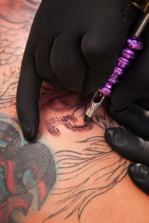 Tatto artist inks a design on client's bodyの写真素材