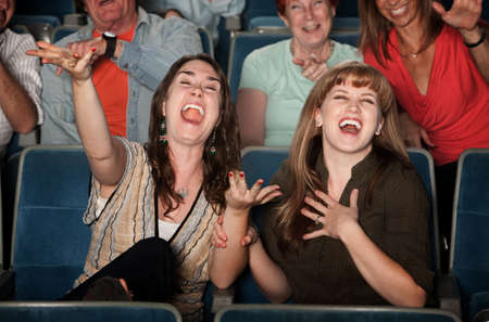 Young women laugh out loud in theater