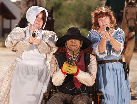 Three people with guns out in old American west scene