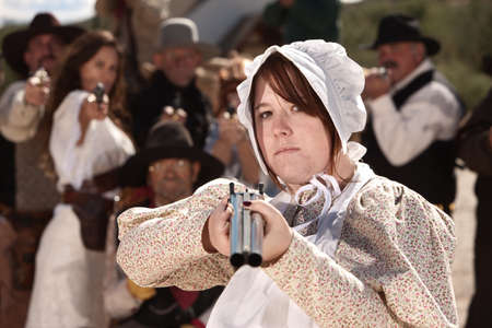 Serious young lady in bonnet pointing a double barrel shotgun