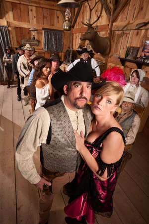 Serious old western couple in crowded saloon