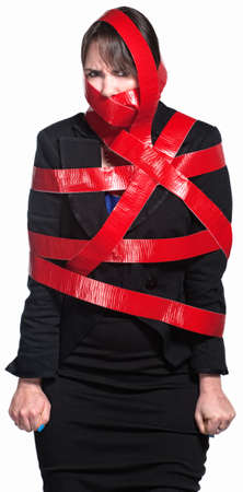 Angry female executive tied up in red tapeの写真素材