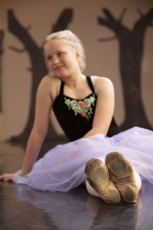 Cute ballet student sitting with shoes in focusの写真素材