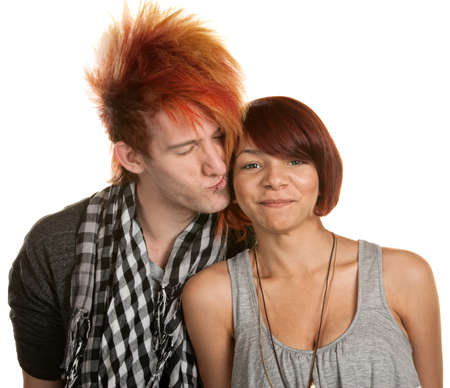 Young man with mohawk kisses mixed girlfriend over whiteの写真素材