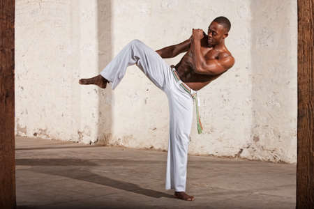Young Black man demonstrating a knee kick indoorsの写真素材