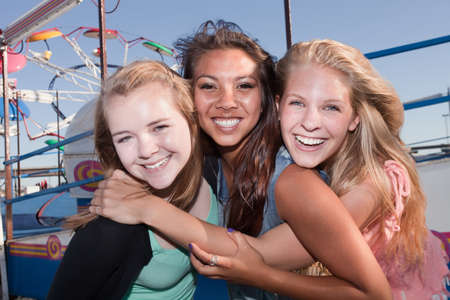 Group of three Asian and white teenage girlfriends at a carnivalの写真素材