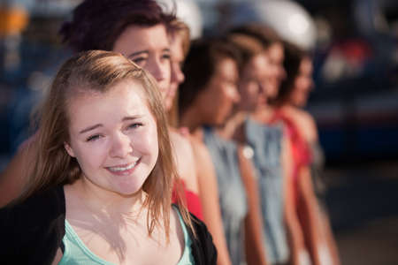 Smiling blond teenage girl in front of groupの写真素材