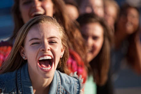 Young happy white teenage girl shouting with friendsの写真素材