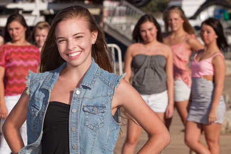 Confident young Caucasian girl in front of jealous friends