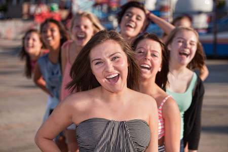 Laughing teenage friends behind one another outsideの写真素材