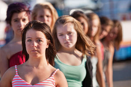 Row of serious teenage girls at an amusement parkの写真素材