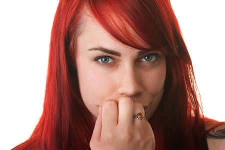 Skeptical young woman with fingers on mouth over white backgroundの写真素材