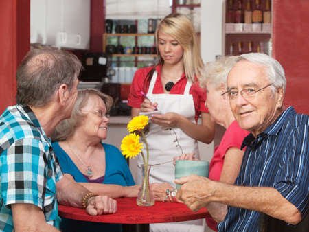 Senior Caucasian male sitting with friends in a cafeの写真素材