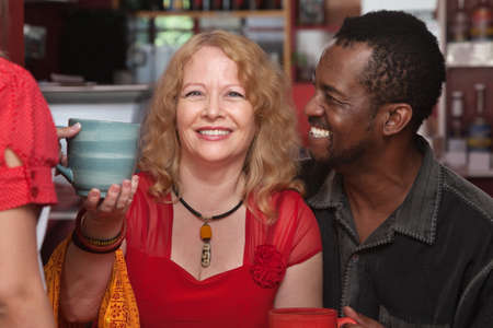 Cheerful African and European couple served coffeeの写真素材