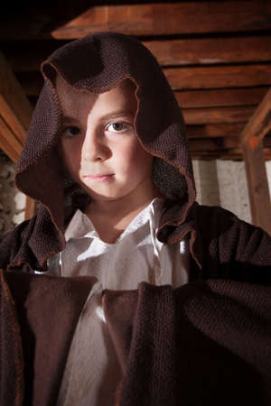 Young magician with folded arms hidden in his cloakの写真素材