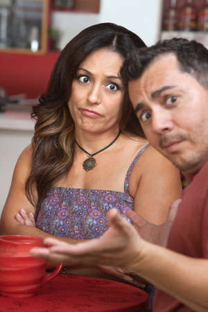 Skeptical Latino woman sitting with man at tableの写真素材
