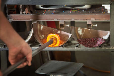 Iron rod with molten glass placed in colored stonesの写真素材