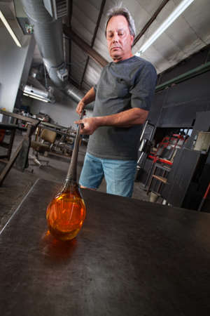 Serious worker with molten glass object on workbenchの写真素材