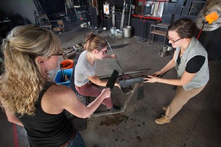 Trio of young white women working on glass art creation