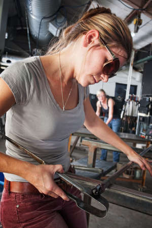 Pretty glass sculptor shaping tiny object on workbench