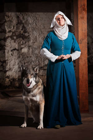 Peaceful medieval nun standing with pet dogの写真素材