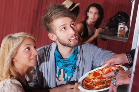 Cute boyfriend and girlfriend picking up pizza order