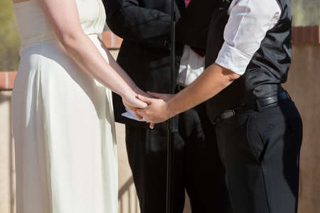 Women holding hands in wedding ceremony outdoorsの写真素材