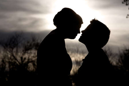 Back lit lesbian couple close together outdoorsの写真素材
